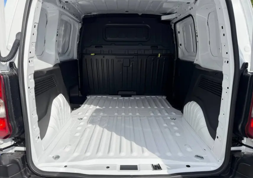 Vue arrière du coffre vide du Peugeot Partner blanc Icy, montrant l'espace de chargement et la cloison noire.