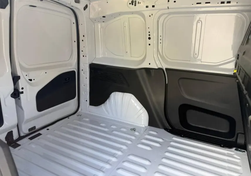 Vue intérieure de la zone de chargement arrière du Peugeot Partner blanc Icy, montrant la cloison pleine et les protections noires.