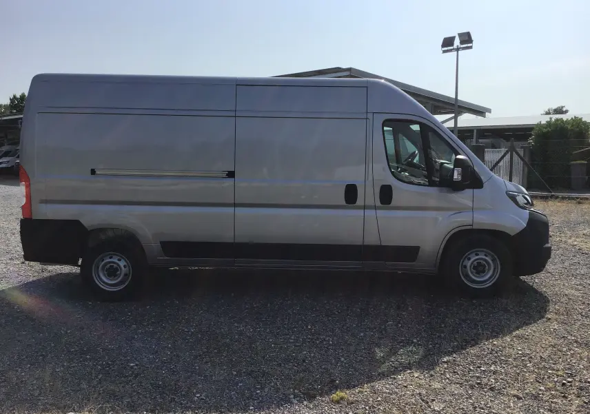 Vue latérale droite d'un Peugeot Boxer Fourgon gris Artense, profil long avec détails noirs contrastants sur les bas de caisse.