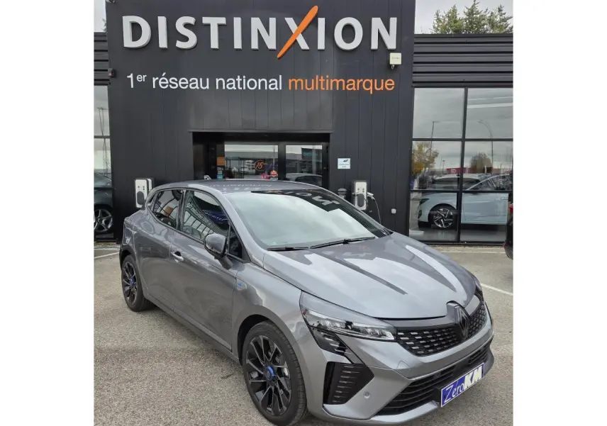 Renault Clio V hybride gris schiste métal vue 3/4 avant avec jantes alliage noires et calandre distinctive.