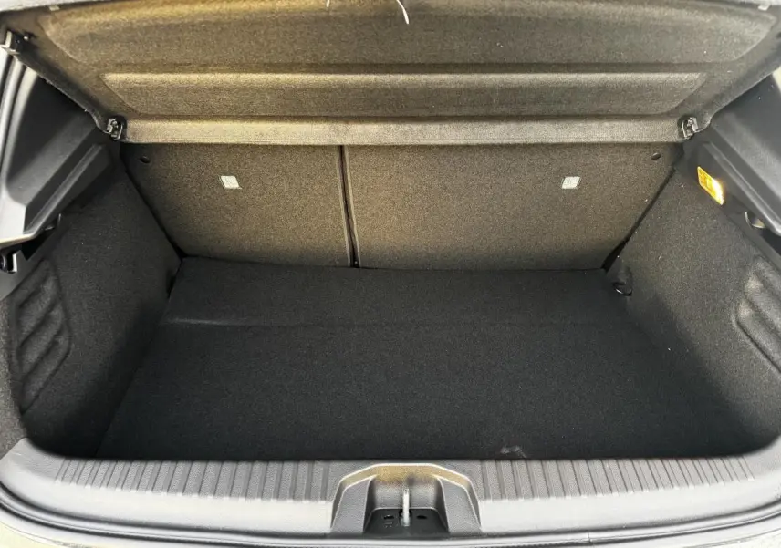 Coffre ouvert de Renault Clio V hybride gris schiste, vue intérieure montrant le volume de chargement vide.