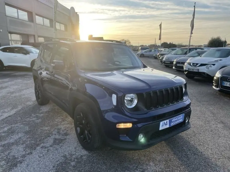 Jeep Renegade bleu Jetset Metal en 3/4 avant droit, avec calandre noire et jantes noires, stationné en extérieur au coucher du soleil.