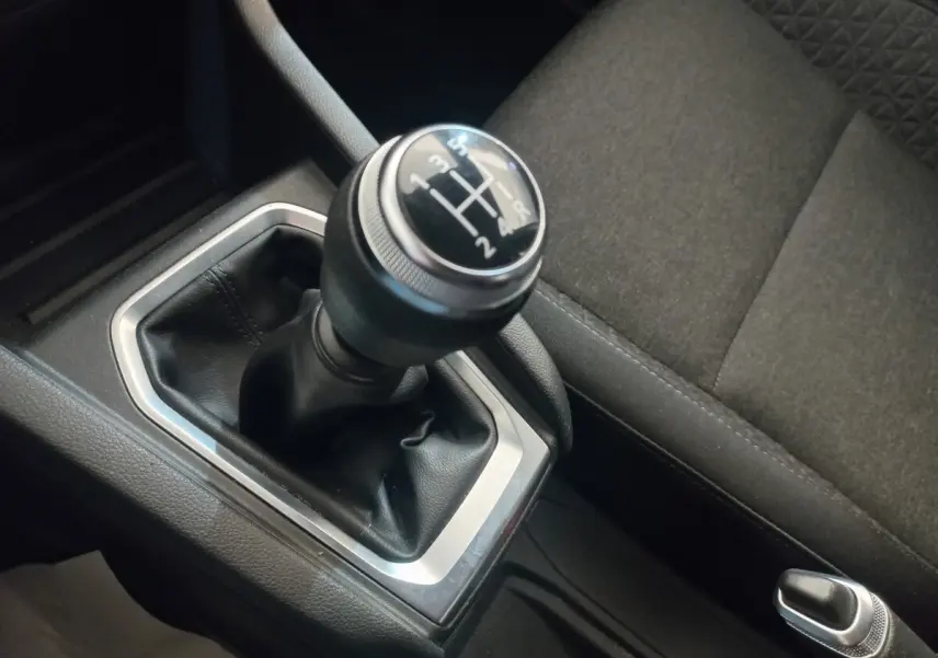 Gros plan sur le levier de vitesses manuel noir et argenté de la Renault Clio Business, avec siège tissu gris à côté.