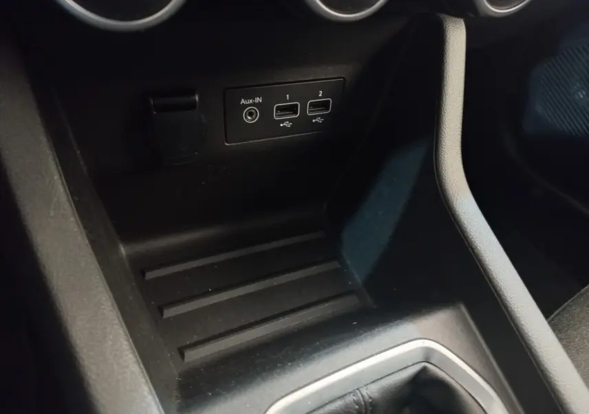 Vue intérieure rapprochée du port USB et prise Aux-IN noirs sur la console centrale d'une Renault Clio blanche.
