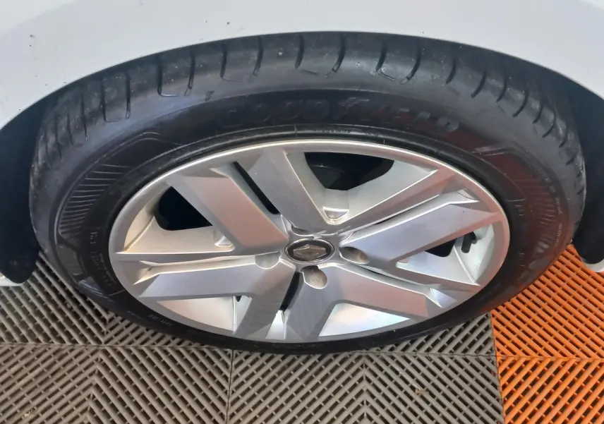 Gros plan sur la roue avant droite d'une Renault Clio blanche, jante alliage à cinq branches doubles.