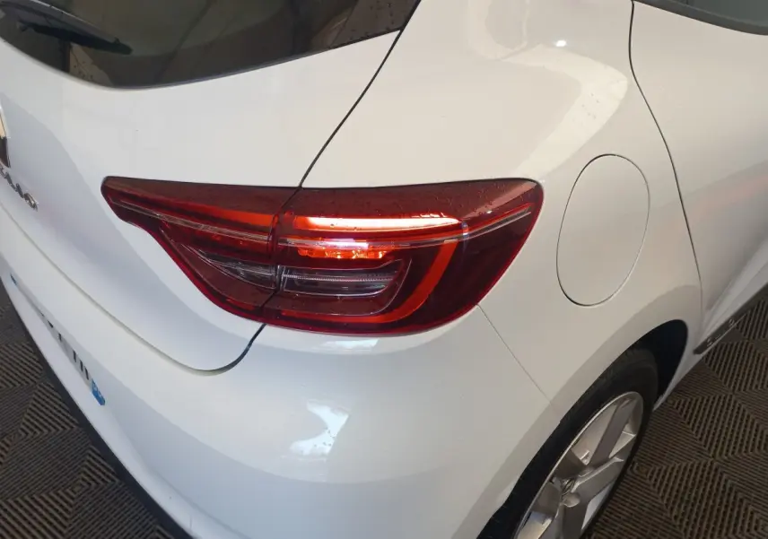 Vue 3/4 arrière droite d'une Renault Clio Business blanche, mettant en valeur le feu arrière LED et la trappe à carburant.