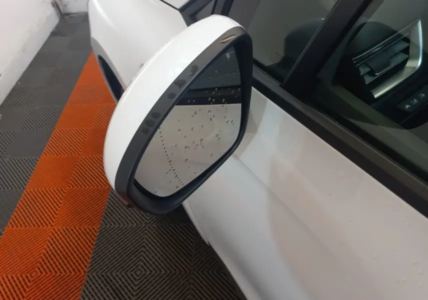 Rétroviseur extérieur gauche blanc de Renault Clio Business 2021 avec gouttes d'eau, vue rapprochée en intérieur.