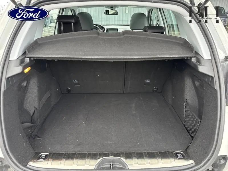 Coffre ouvert vu de l'arrière d'une Peugeot 2008 Blanc Banquise, espace de chargement vide avec cache-bagages.