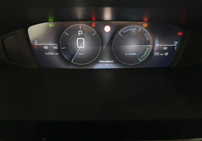 Vue rapprochée du combiné d'instruments numérique du Peugeot 308 Hybrid 145 e-DCS6 Allure affichant vitesse, charge et alertes.