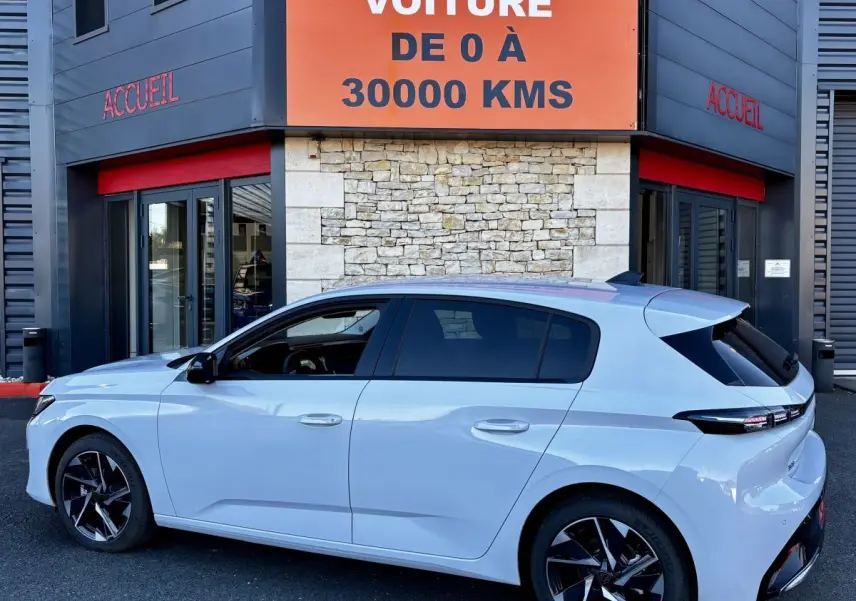 Vue latérale droite d'une Peugeot 308 Hybrid 145 e-DCS6 Allure blanche, avec jantes noires et vitres teintées.