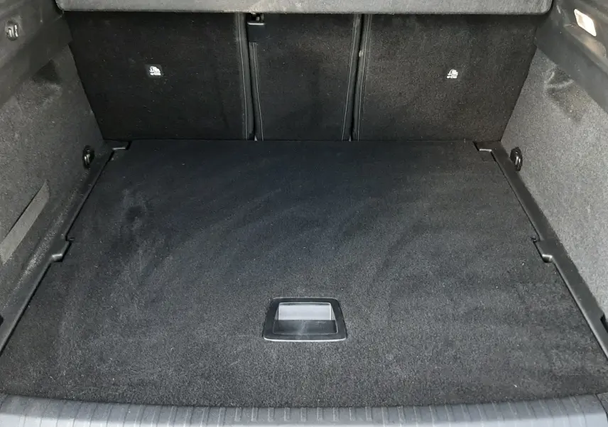 Vue intérieure du coffre spacieux et propre du Peugeot 3008 1.2 Hybrid 145ch GT bleu Ingaro, sans chargement.