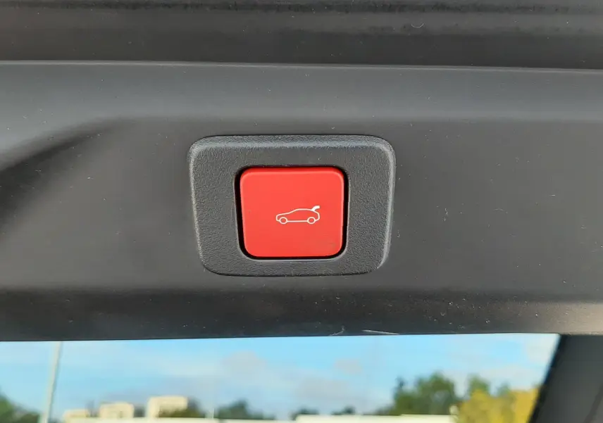 Bouton rouge de fermeture automatique du hayon visible à l'intérieur arrière du Peugeot 3008 bleu Ingara 2025.