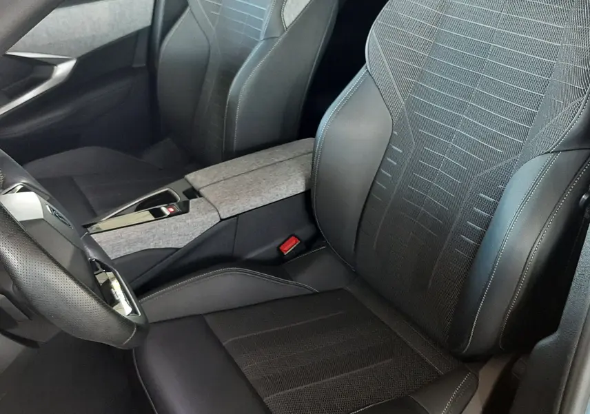 Vue intérieure rapprochée des sièges avant en cuir et tissu noir avec surpiqûres blanches du Peugeot 3008 Bleu Ingara 2025.