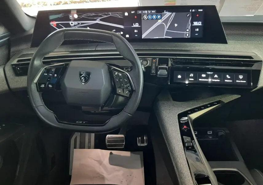 Vue intérieure du tableau de bord du Peugeot 3008 Hybrid 2025, avec volant multifonction et écran numérique panoramique.