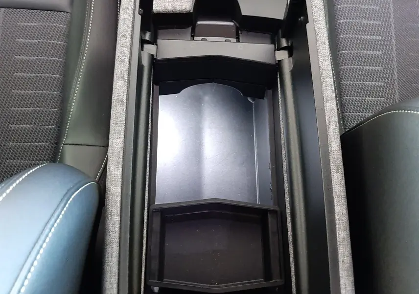 Vue plongeante sur le rangement central ouvert du Peugeot 3008 1.2 Hybrid 145ch GT, intérieur noir avec accoudoir bleu Ingaro.