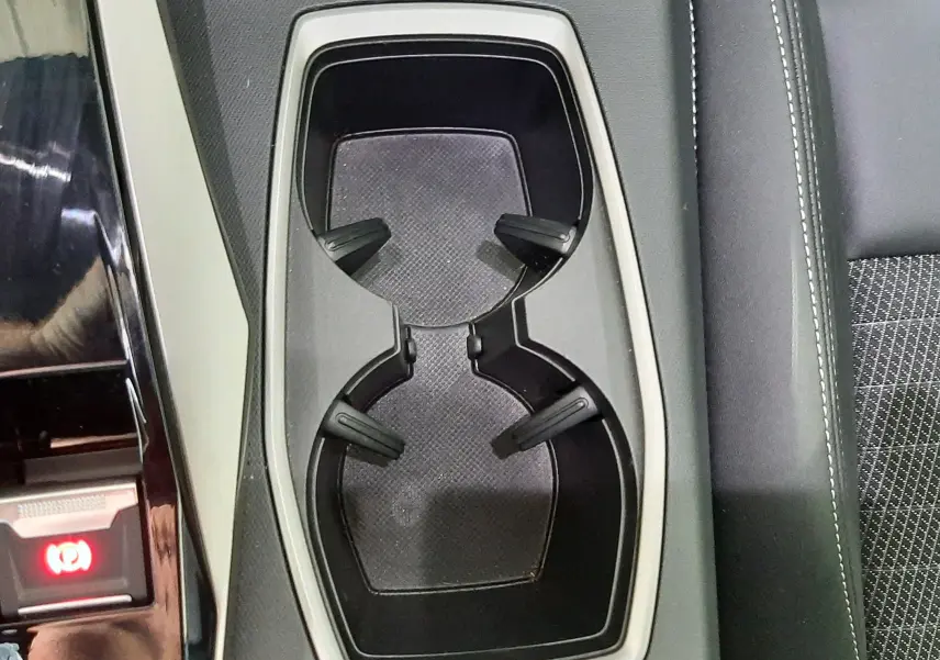 Gros plan sur les porte-gobelets centraux et accoudoir en cuir noir du Peugeot 3008 Hybrid 2025.