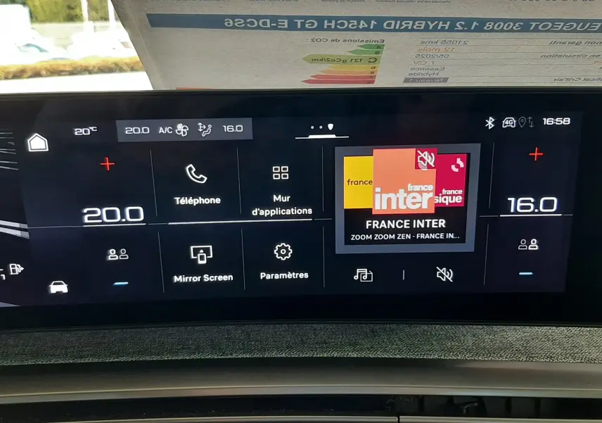 Vue rapprochée de l’écran tactile central et console de la Peugeot 3008 Hybrid 2025, affichant la radio et la climatisation.