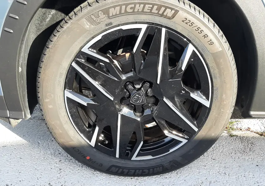 Gros plan sur la roue avant droite du Peugeot 3008 bleu Ingaro avec jante noire et détails argentés, pneu Michelin.