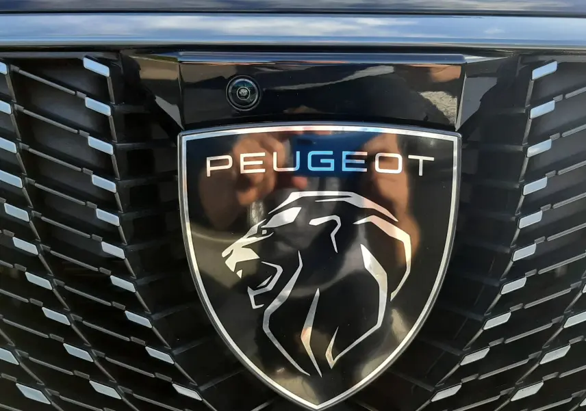 Gros plan sur la calandre noire brillante du Peugeot 3008 2025 avec logo lion et inscription 3008 en relief.