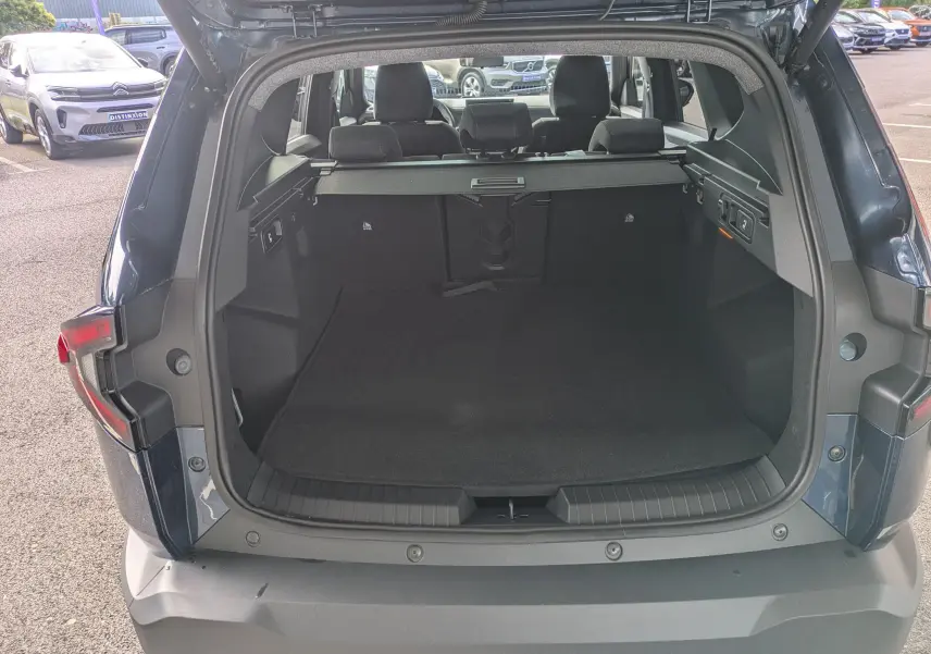 Coffre ouvert vu de l'arrière du Dacia Bigster Bleu Indigo, montrant l'espace de chargement et la banquette arrière.