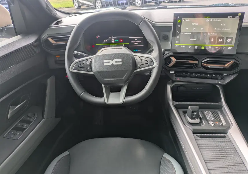 Vue intérieure centrée sur le volant et tableau de bord du Dacia Bigster Hybrid 155, avec écran tactile et console moderne.