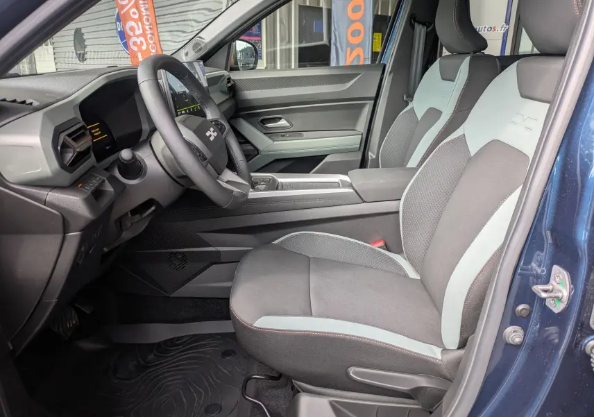 Intérieur avant droit du Dacia Bigster Hybrid 155 Extreme bleu indigo, sièges bi-ton gris avec volant multifonction.