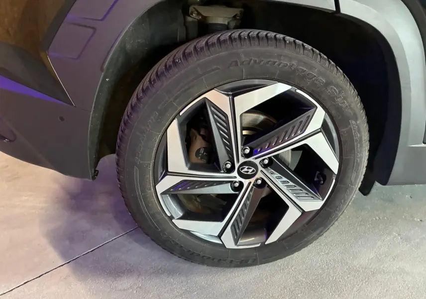 Gros plan sur la roue avant droite du Hyundai Tucson noir 2022 avec jante alliage au design moderne.