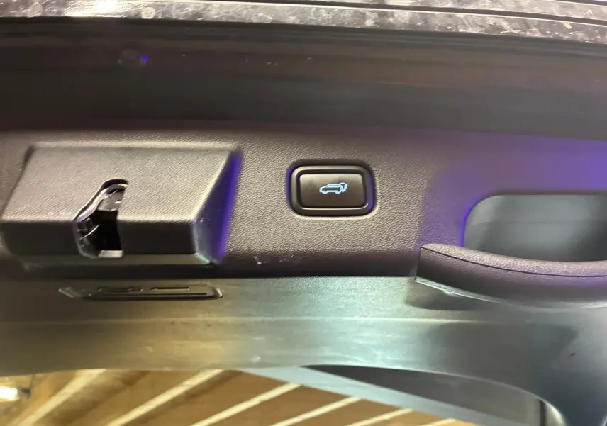 Détail du bouton d'ouverture électrique du coffre sur la porte arrière d'un Hyundai Tucson noir 2022.