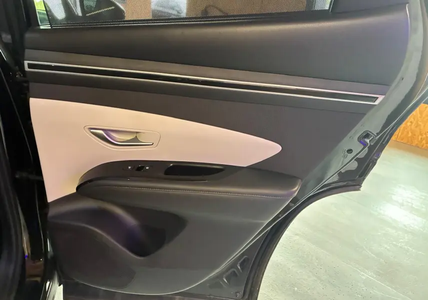 Vue rapprochée de la porte arrière gauche noire du Hyundai Tucson 2022 avec garniture intérieure bicolore beige et noire.