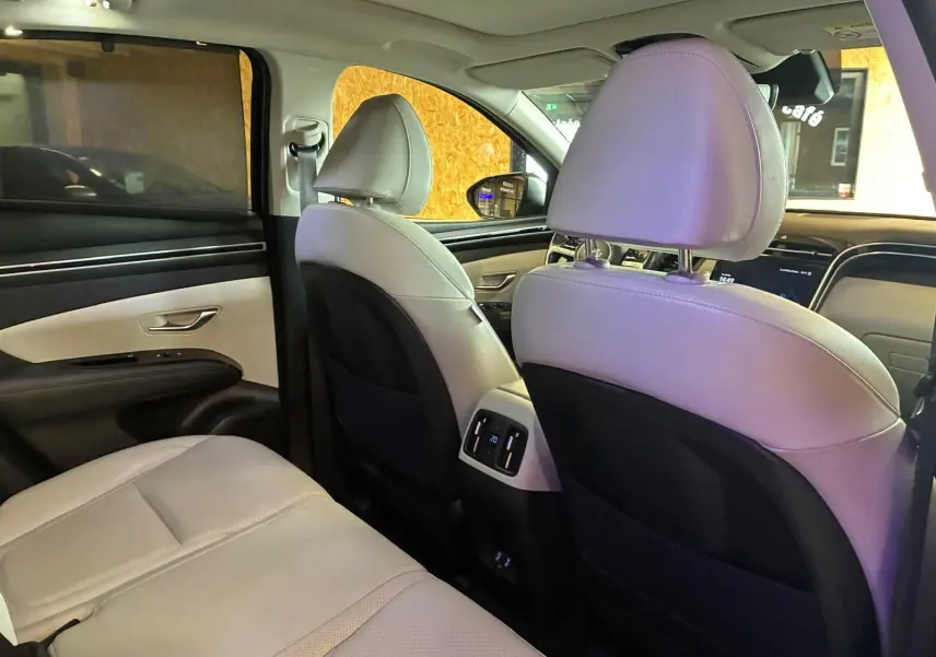 Vue intérieure arrière du Hyundai Tucson 2022, sièges en cuir beige avec détails noirs et commandes climatisation arrière.