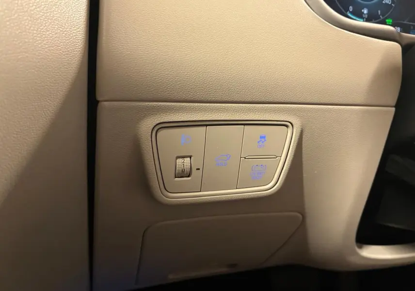 Détail des commandes éclairage et assistances sur panneau beige côté gauche du tableau de bord du Hyundai Tucson noir 2022.
