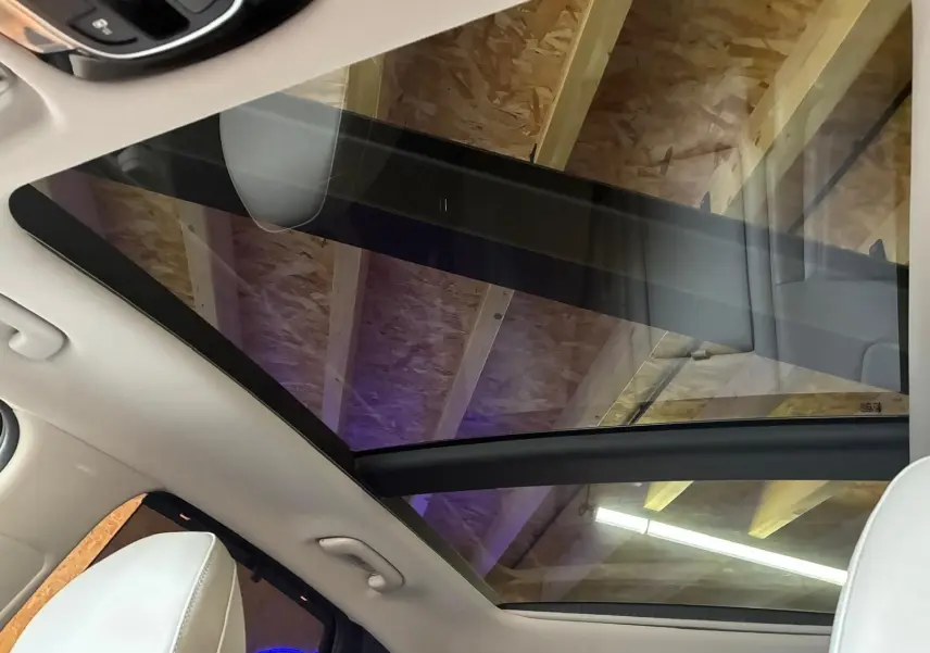 Vue intérieure du toit panoramique en verre du Hyundai Tucson noir, avec sièges cuir beige visibles au premier plan.