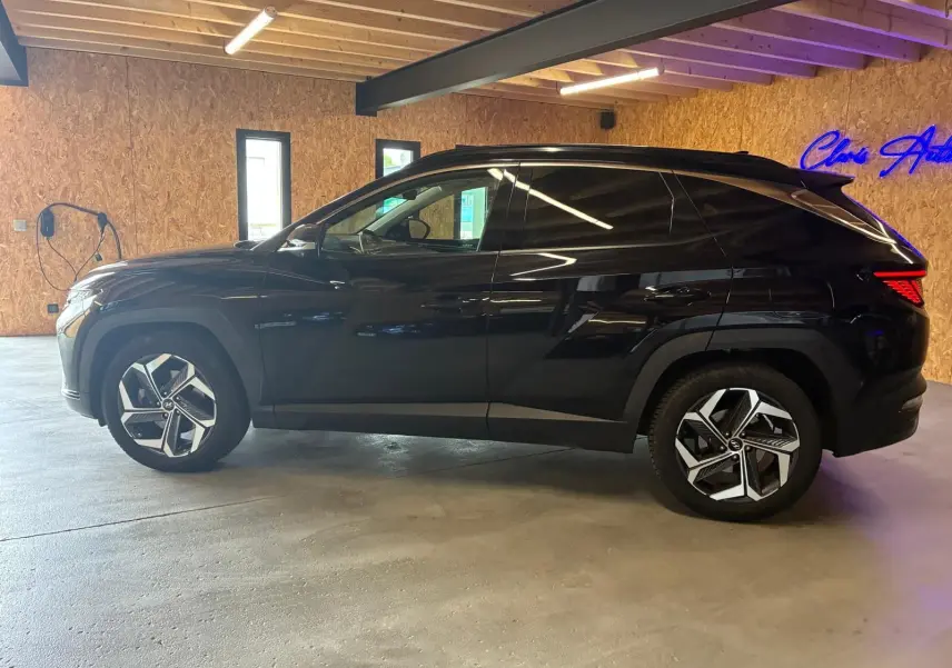 Vue de profil côté gauche du Hyundai Tucson noir 2022, mettant en valeur ses jantes modernes et sa silhouette compacte.