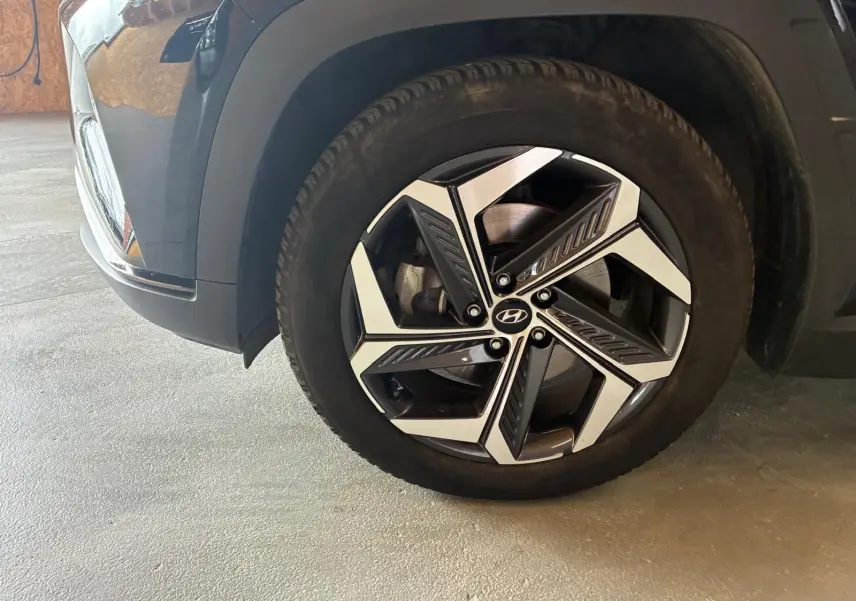 Gros plan sur la roue avant droite noire du Hyundai Tucson 2022 avec jante alliage bicolore au design moderne.