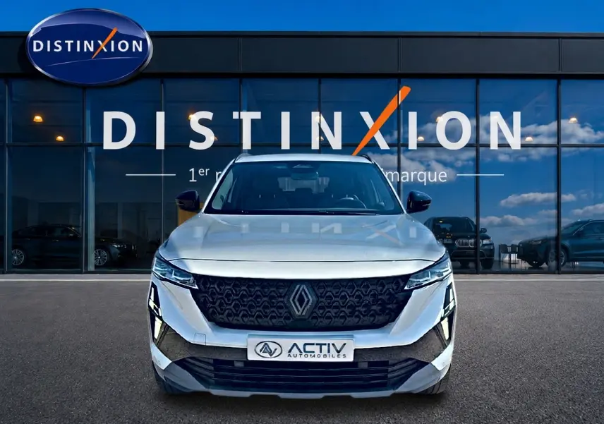 Vue avant d'un Renault Austral blanc nacré avec calandre noire et phares LED, devant une vitrine Distinxion.