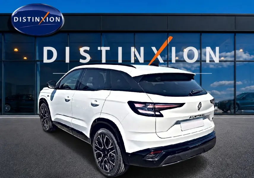 Vue 3/4 arrière droite du Renault Austral blanc nacré avec jantes noires devant une vitrine Distinxion.