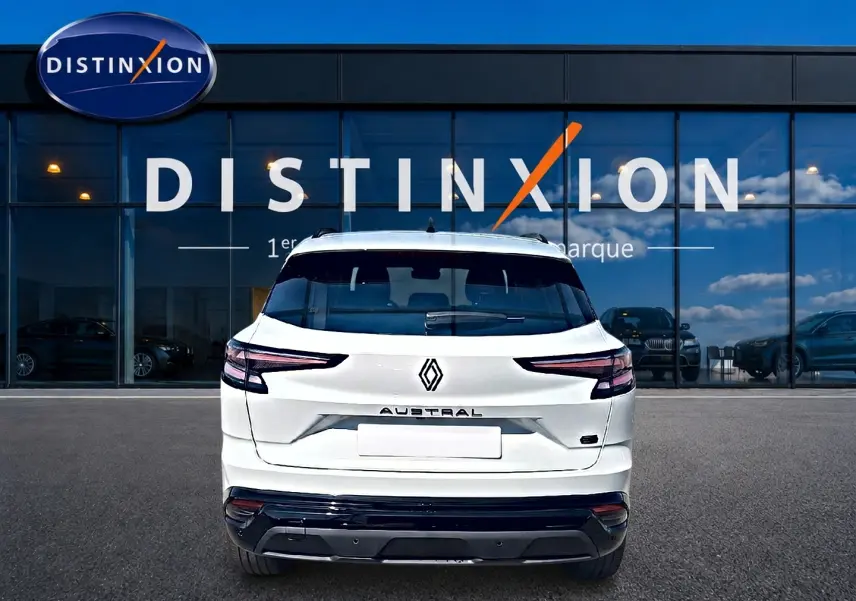 Vue arrière d'un Renault Austral blanc nacré garé devant une vitrine avec logo Distinxion.