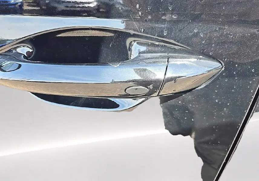 Poignée de porte chromée en gros plan sur la portière noire du Hyundai Tucson 2026 hybride.