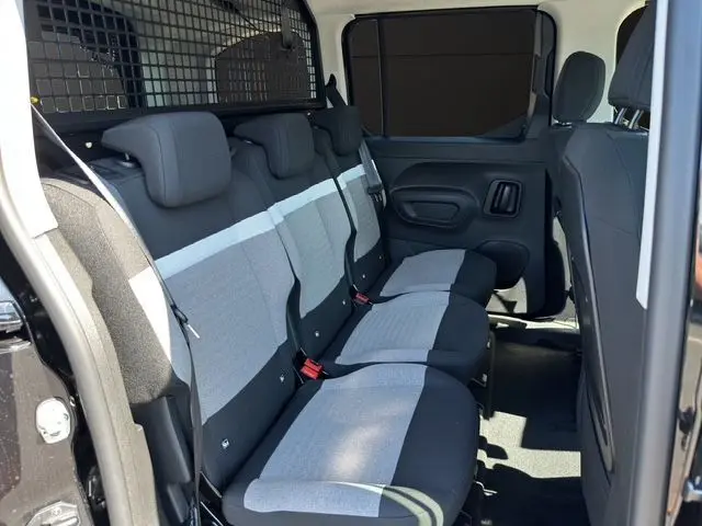 Vue intérieure côté droit des sièges arrière gris et noir du Citroën Berlingo N1 BlueHDi 130 2025 avec cloison métallique.