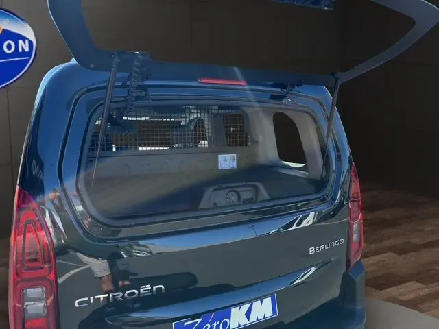 Vue intérieure du coffre du Citroën Berlingo noir 2025, montrant la cloison métallique de séparation et l'espace de chargement.