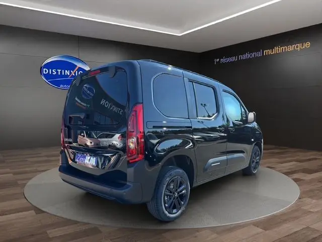 Vue 3/4 arrière droite d'un Citroën Berlingo noir 2025 avec jantes noires et caméra de recul en showroom.