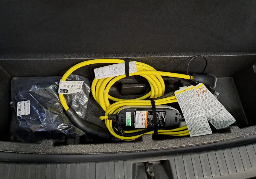 Câble de recharge jaune enroulé dans le coffre d'un Skoda Kodiaq noir Magic nacré, vue de dessus.