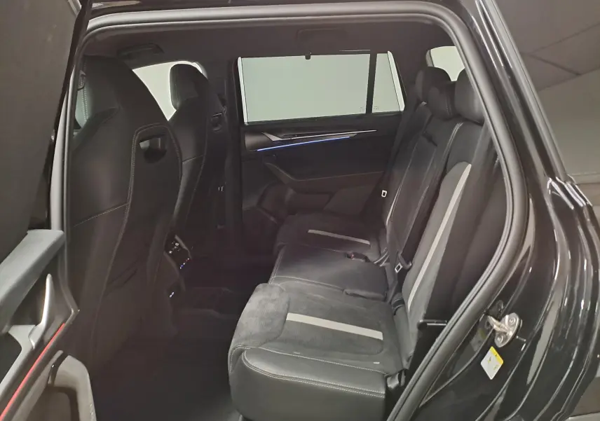 Vue intérieure arrière côté droit du Skoda Kodiaq noir Magic nacré, sièges en cuir et alcantara avec éclairage d'ambiance bleu.