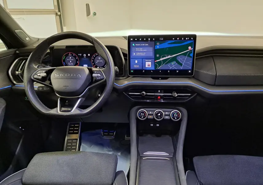 Vue intérieure avant du Skoda Kodiaq 2025, tableau de bord noir avec écran tactile central et volant multifonctions.