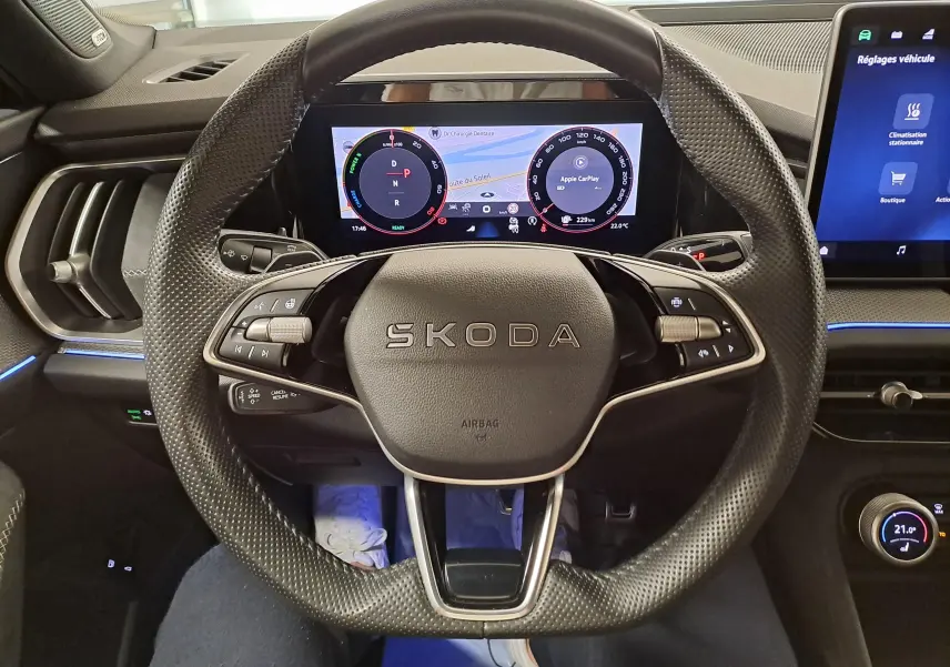 Vue rapprochée du volant perforé noir du Skoda Kodiaq 2025 avec tableau de bord numérique et écran tactile latéral.