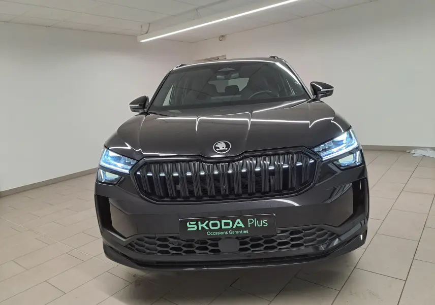 Vue frontale d’un Skoda Kodiaq noir Magic nacré avec calandre noire et phares LED allumés en intérieur.