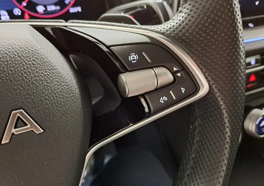 Gros plan sur le volant en cuir perforé du Skoda Kodiaq 2025 avec commandes multifonctions et molette argentée.