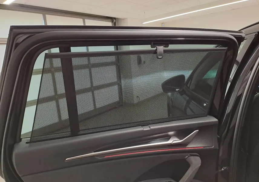 Vue intérieure de la porte arrière gauche d’un Skoda Kodiaq noir Magic nacré avec pare-soleil intégré et garniture noire.