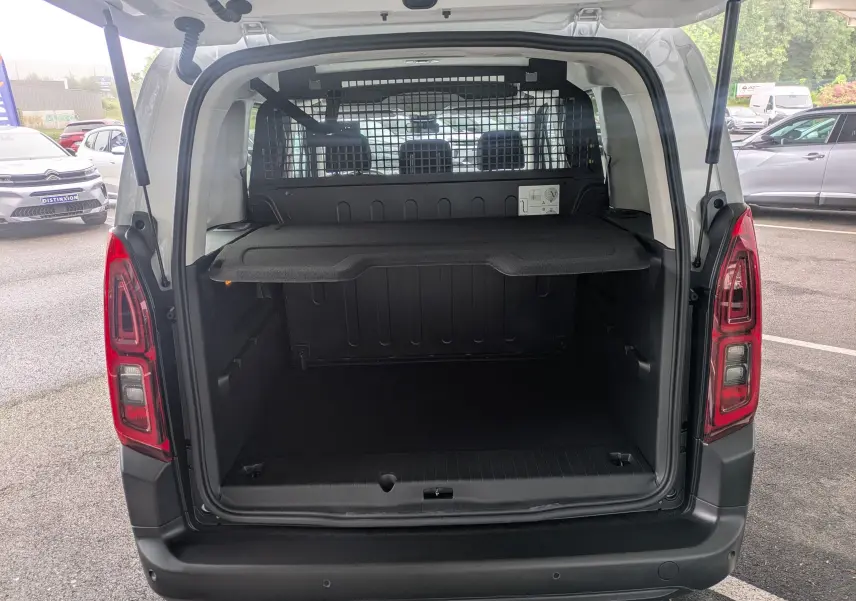 Vue arrière ouverte du Citroën Berlingo blanc 2025, montrant le coffre spacieux avec séparation grillagée.