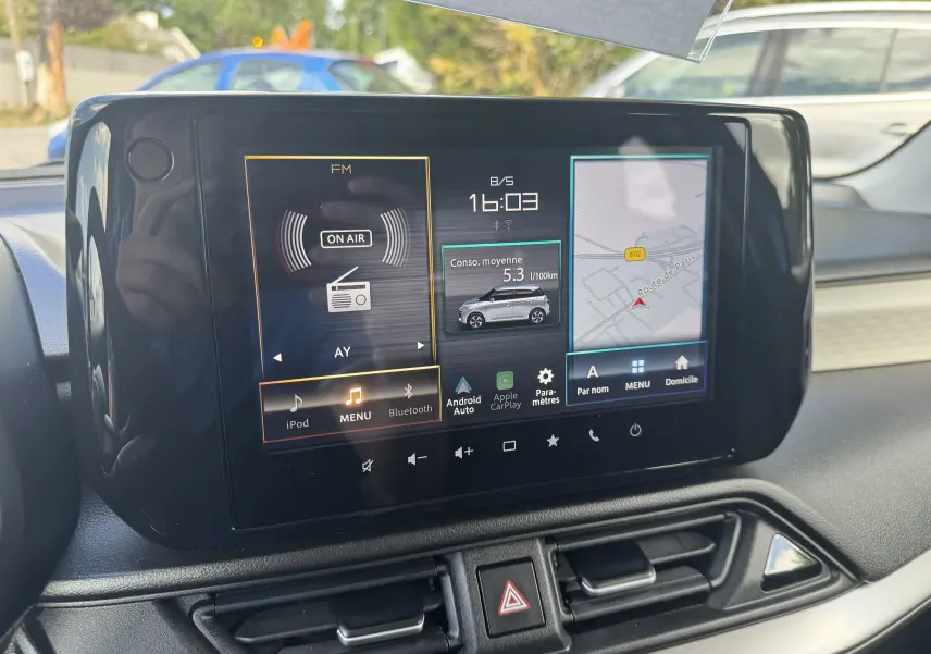 Écran tactile central de la Suzuki Swift 1.2 Pack Hybrid 2024 affichant radio, consommation moyenne et navigation.